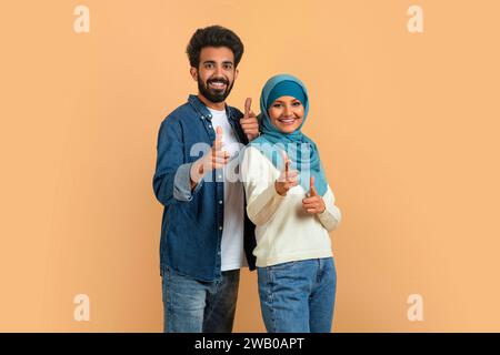 Gotcha. Cheerful Muslim Couple Pointing Fingers At Camera, Indicating Somebody Stock Photo