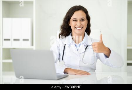 Positive european woman doctor working on laptop at clinic Stock Photo
