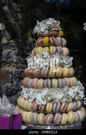 A wedding pyramid of French meringue macarons. Pink, yellow, purple and pink colored macarons in rows with layers of cookies and flowers. Stock Photo