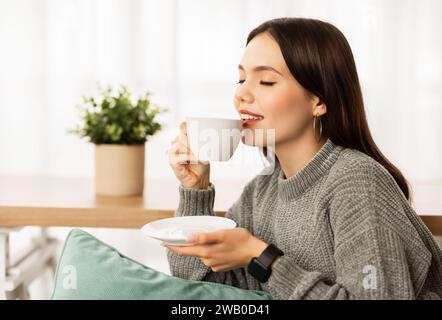 Closeup of happy young woman drinking coffee at home Stock Photo