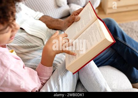 Cropped of senior man and boy reading book at home Stock Photo