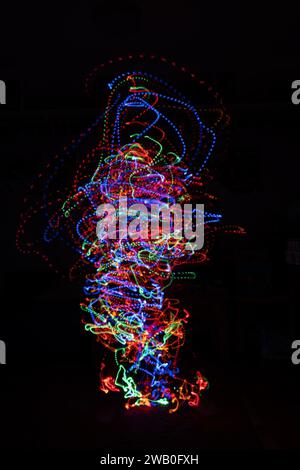 Colourful burst of lights in a chaotic motion simulating a tornado or explosion of beaded light on a black background. Stock Photo