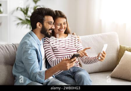 Positive millennial man and woman using cell phones at home Stock Photo