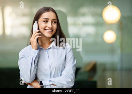 Confident young professional woman engaging in a pleasant conversation over her phone Stock Photo