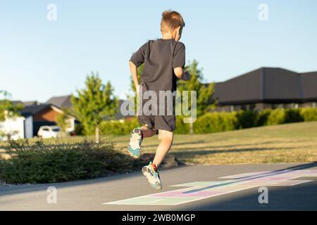 A boy is playing hopscotch on the asphalt in the playground. Active leisure for children.  Stock Photo