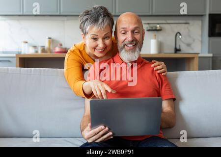 Smiling Senior Spouses With Laptop Shopping Online Together At Home Stock Photo