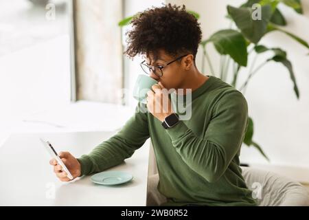 Relaxed millennial black man drinking coffee at cafe Stock Photo