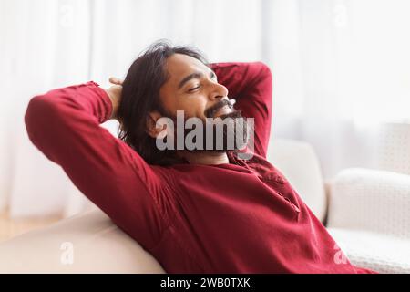 Relaxed millennial eastern man resting on couch at home Stock Photo