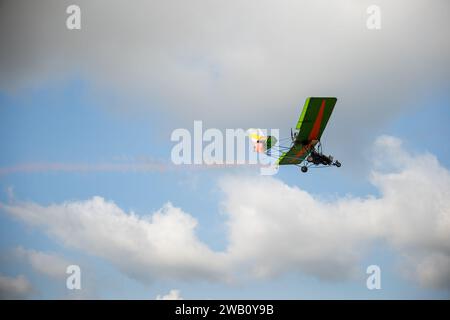 Aerobatic airplane emits smoke trail in stunning performance against blue sky. Skilled pilot Stock Photo