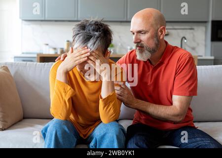 Caring elderly husband comforting his crying wife at home Stock Photo