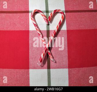 Candy cane hearts on red and white laid background Stock Photo