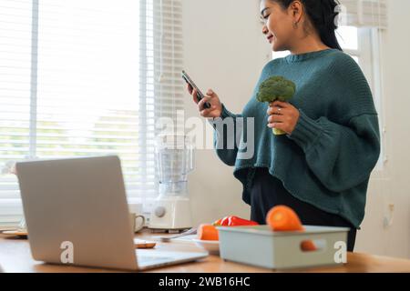 Beautiful smile fat woman cooking while using mobile phone in the kitchen at home Stock Photo