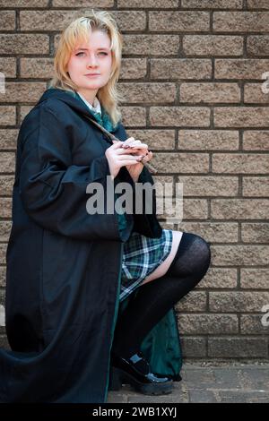 A blonde Caucasian female cosplayer dressed as a wizard with a magic wand Stock Photo