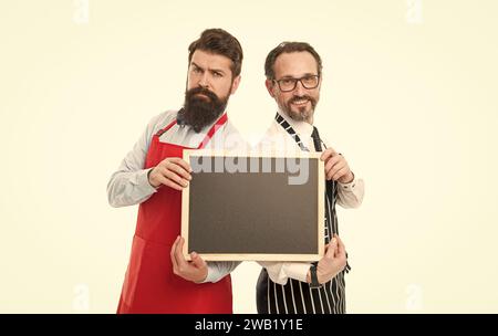 Men bearded bartender in apron hold blank chalkboard. Bartender with blackboard advertisement. Hipster bartender show blackboard copy space. Join us Stock Photo