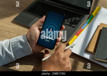 A voice recording man holding his smartphone screen generates AI technology for language and communication in a mobile application. Record sound Stock Photo