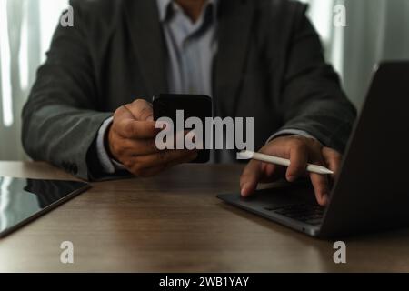 businessman working uses a mobile texting cell phone to contact us business and connect on a desk computer work job at workplaces Stock Photo