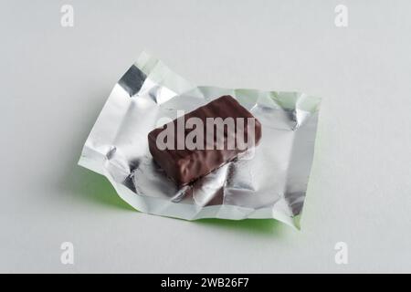 Unwrapped chocolate candy. Close-up. Isolated on a gray background. Stock Photo