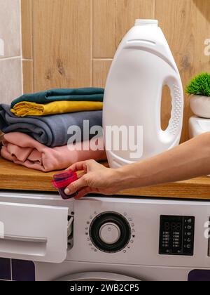 the girl pours the washing gel into the washing machine Stock Photo