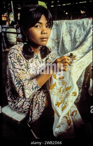 Indonesia, Java - In a batik factory a woman applies wax to a cloth and then have it dyed so that it becomes a traditional batik. Stock Photo