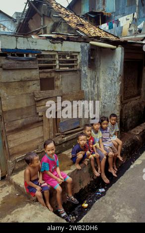Indonesia, Java children sit above an open sewer in a slum Stock Photo