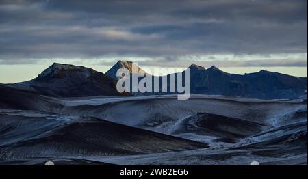 Snowy mountain ridge under cloudy sky at dusk Stock Photo