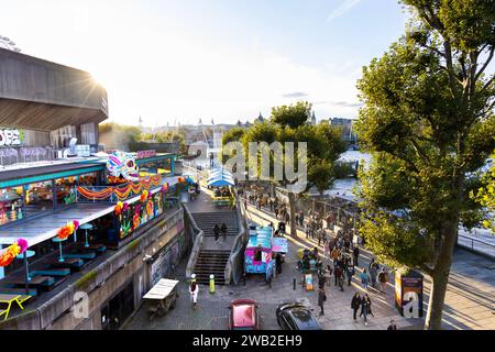 People walking down the Southbank with brutalist Southbank Centre on the left, London, England Stock Photo
