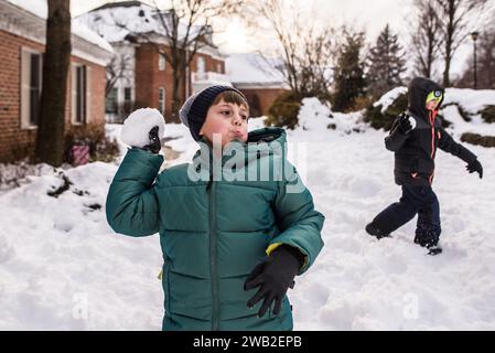 Boys in snow gear get ready to throw snowballs in yard Stock Photo