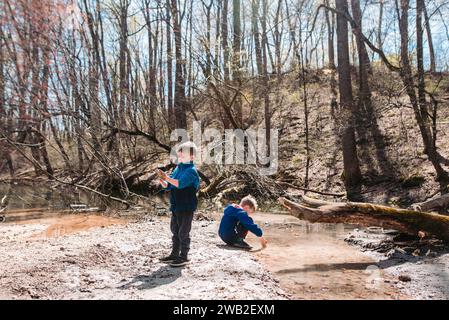 Two young children explore in muddy forest Stock Photo