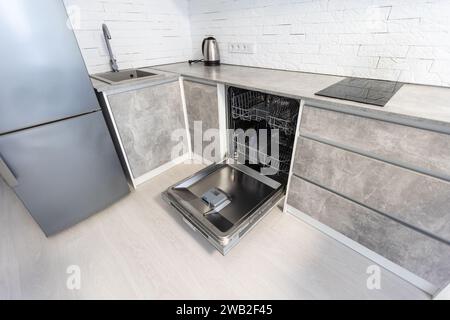 Spacious luxury well designed modern grey, beige and white kitchen with marble tiles floor. Door of electric oven ais open Stock Photo