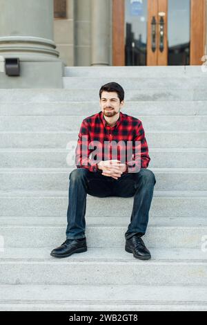 Young man in red sitting in front of court house Stock Photo
