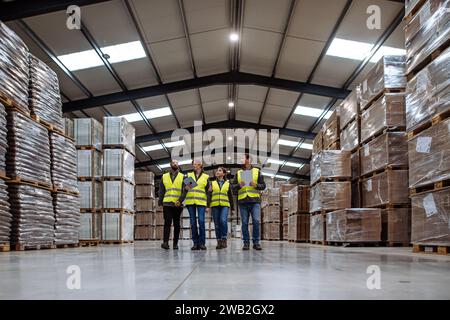 Front view of warehouse workers walking in warehouse. Team of warehouse workers preparing products for shipment. Stock Photo