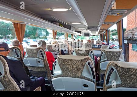 Coach passengers interior back view mostly grey hair senior heads sitting comfortably for summer hotel based touring holiday in East Anglia England UK Stock Photo