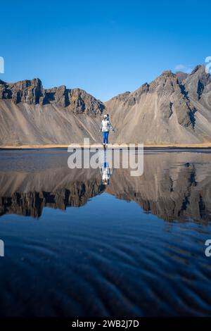 A vertical of a young Caucasian woman posing against a lake on a sunny day Stock Photo
