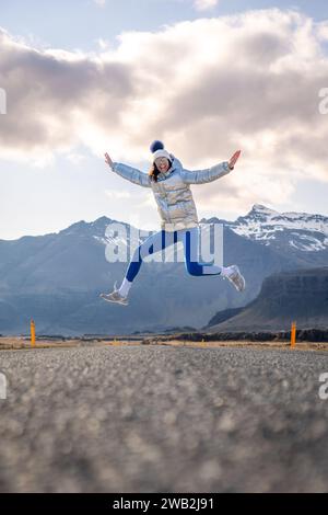 A young female skateboarder executing an airborne trick, jumping joyfully in the air with her board Stock Photo
