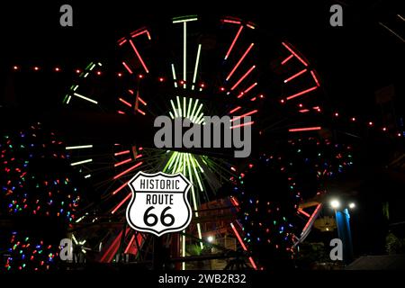 Night shot of the famous Route 66 sign in front of the Ferris wheel, all lit up. Santa Monica pier, Los Angeles, California, USA Stock Photo