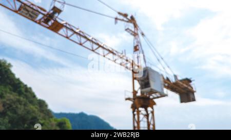 Blur background close-up view from a drone of a construction crane cabin against the backdrop of beautiful sea, sky and mountain. Construction concept Stock Photo