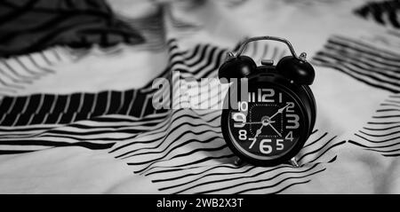 Black alarm clock on bed. Time to wake up Stock Photo