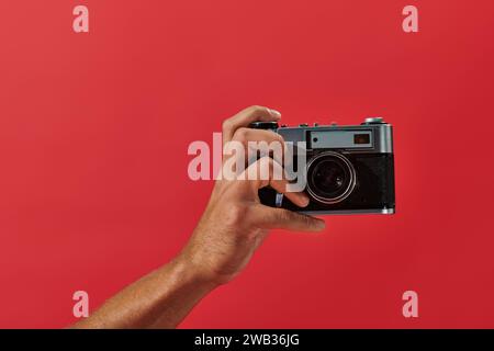 cropped view of african american photographer taking shot on retro camera on red background Stock Photo