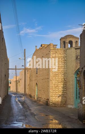 Traditional windcatcher on the roof and hanging power cables in a quite alley in Yazd, Iran. Stock Photo