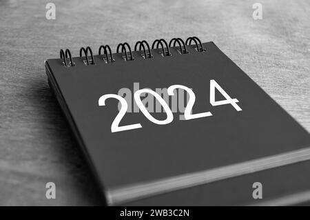 Black and white Year 2024 desk calendar on wooden desk. New Year and calendar concept. Stock Photo