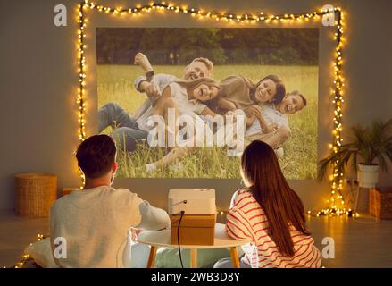Projection family pictures on wall, using video projector, happy people in love sitting close Stock Photo