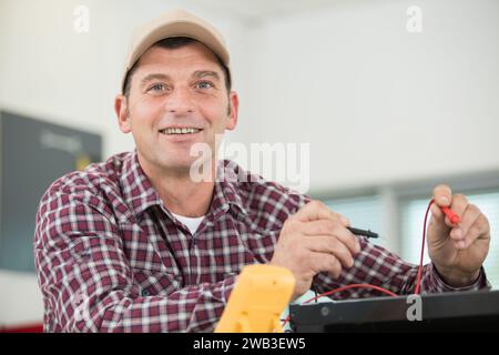 handsome cheerful electrician repairing electrical box Stock Photo