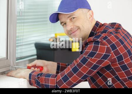 worker fasten the handle to a plastic window Stock Photo