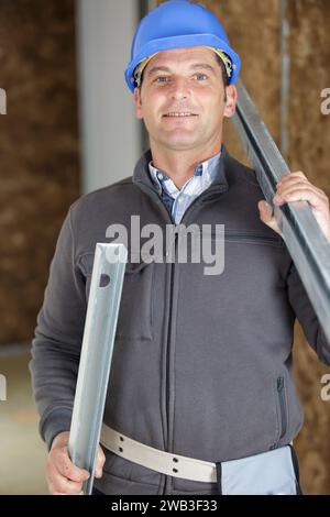 smiling construction worker carrying a metal bar Stock Photo