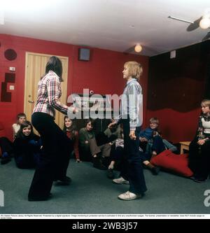 Teenage party in the 1970s. A group of teenagers have arranged a party and a boy and a girl is dancing to the music from the jukebox. Notice the wide legged jeans type that was typical of the decade. Sweden 1970s. Photo Kristoffersson Stock Photo