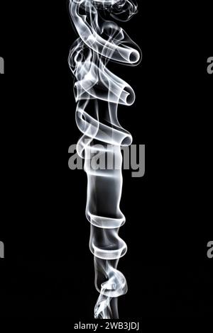 A studio photograph of incense smoke rising against a black background, lit by flash, showing the turbulence caused by air currents Stock Photo