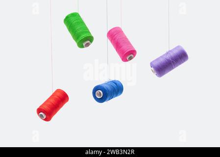 Various spools of sewing cotton thread of different colors floating. Stock Photo