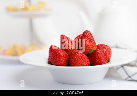 Heap of fresh strawberries in ceramic bowl on rustic white background Stock Photo