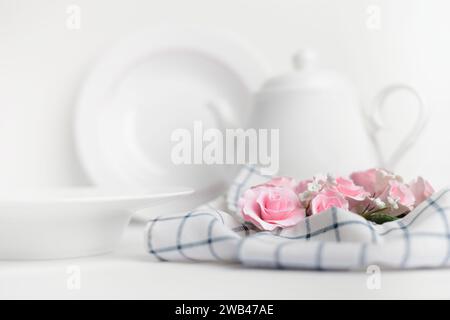 Table setting with pink roses and teapot on a white background Stock Photo