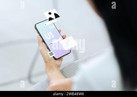 Process of creating an interface for a mobile app. User interface and experience concept. Modern app on smart phone in woman hands Stock Photo